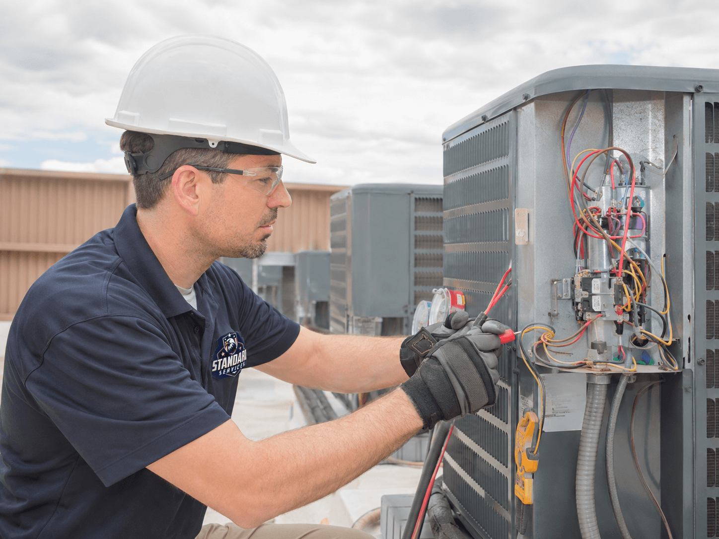 Standard Services technicians installing a new air conditioning condenser unit at a Glen Mills, PA home